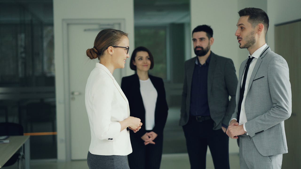 Home Group of professionals in formal attire having a discussion in a modern office setting.