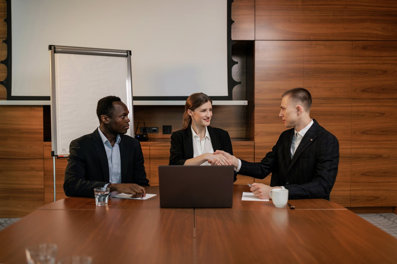 Home Three business professionals shaking hands during a meeting in an office.