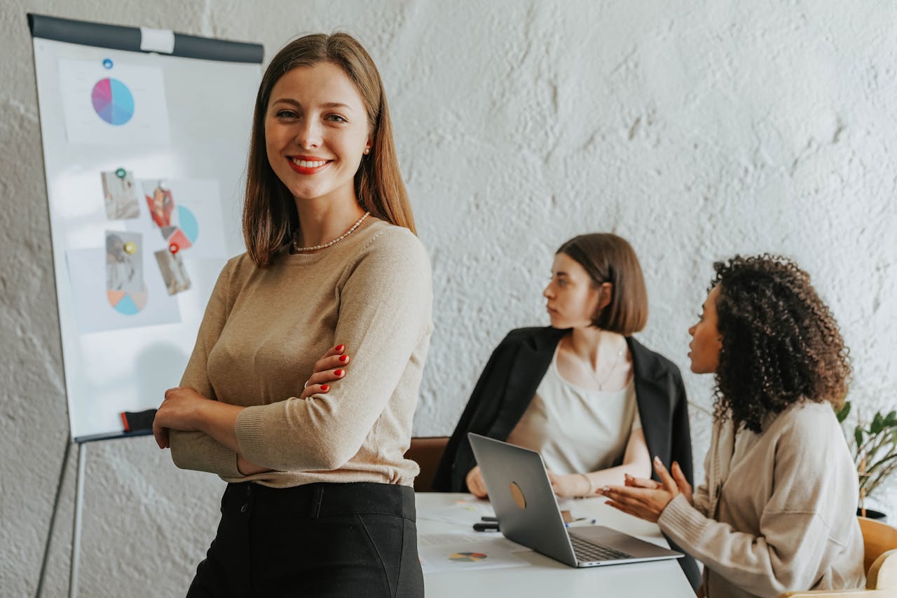 Offerings Confident woman smiling in a modern office setting with colleagues at work.